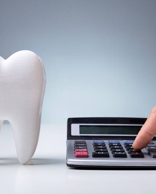 Giant tooth next to calculator on grey background 