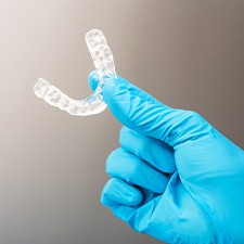 A gloved hand holding a customized nightguard