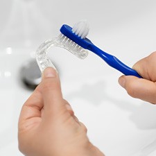 A patient using a toothbrush to clean their nightguard