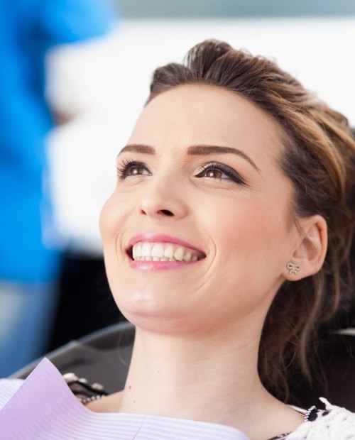 Woman in dental chair smiling up at dentist