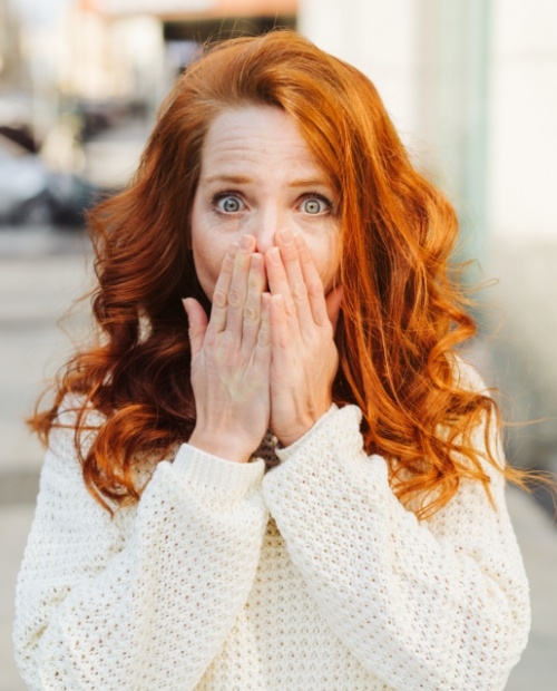 Woman in need of emergency dentistry covering her mouth