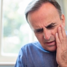 Man with broken tooth holding jaw in pain