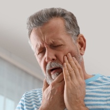 Man with lost filling holding cheek in pain