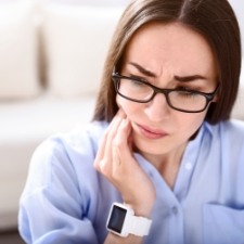 Woman with jaw pain holding cheek