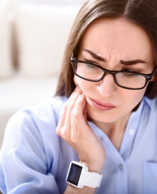 Woman in need of T M J therapy holding jaw