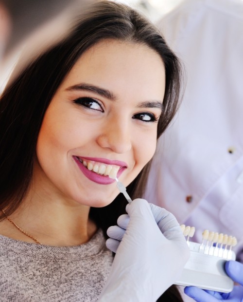 Woman's smile compared with porcelain veneer shade option during cosmetic dentistry visit