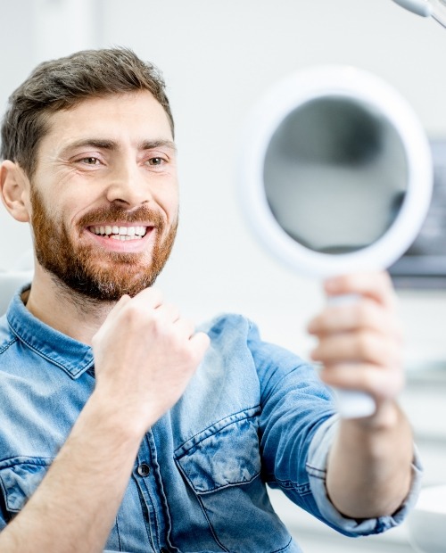 Man looking at smile in mirror after makeover