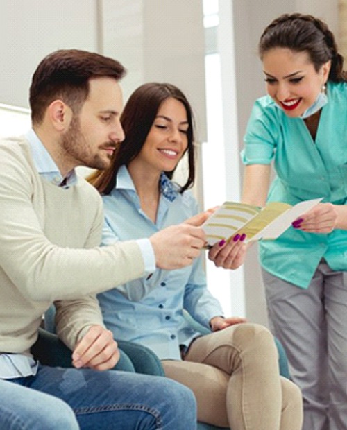 dental team member showing a pamphlet to two patients