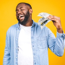 smiling man holding several hundred dollar bills