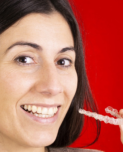 Woman smiling and holding Invisalign in Billerica