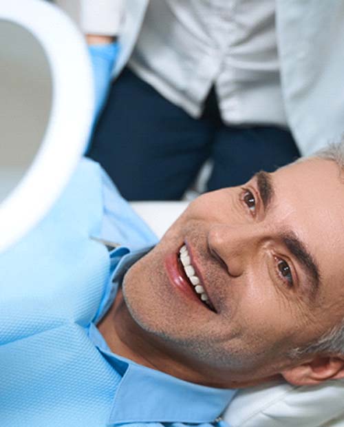 Man with veneers in Billerica smiling in mirror