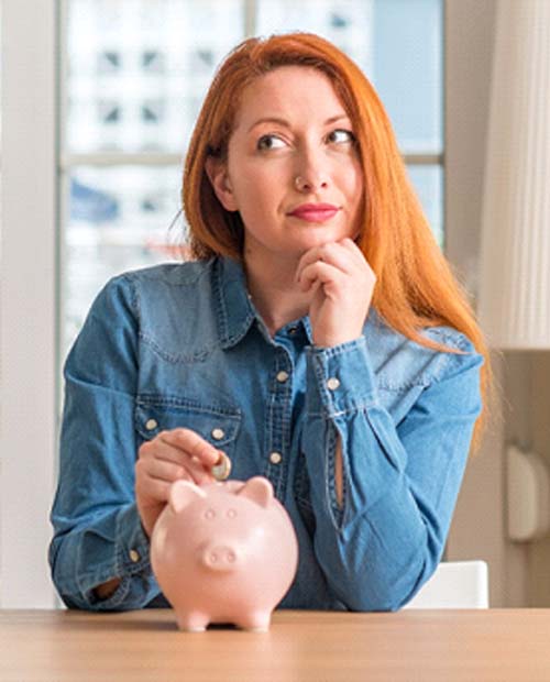 Woman putting coin in piggy bank for cost of veneers in Billerica