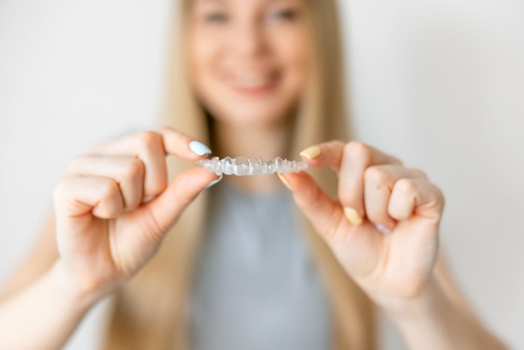 Woman holding up Invisalign aligner