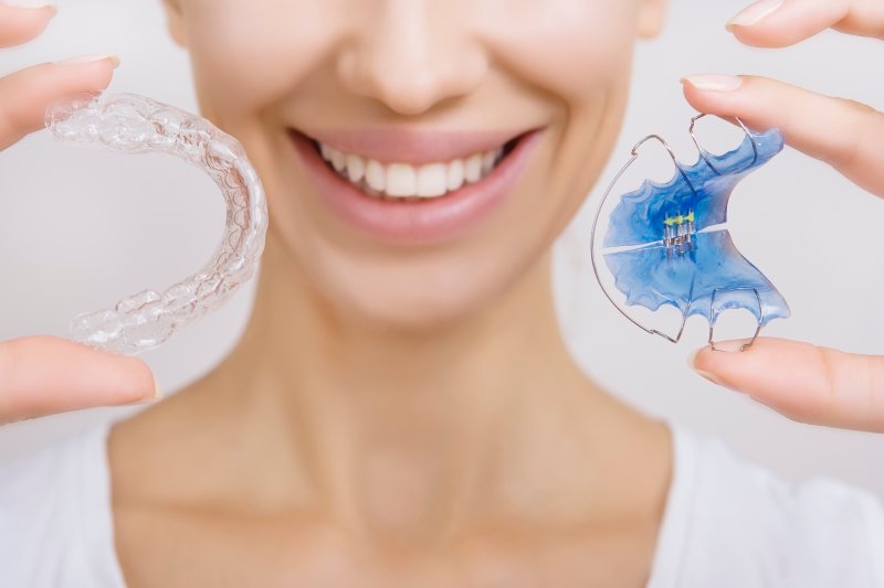 patient smiling while holding retainers