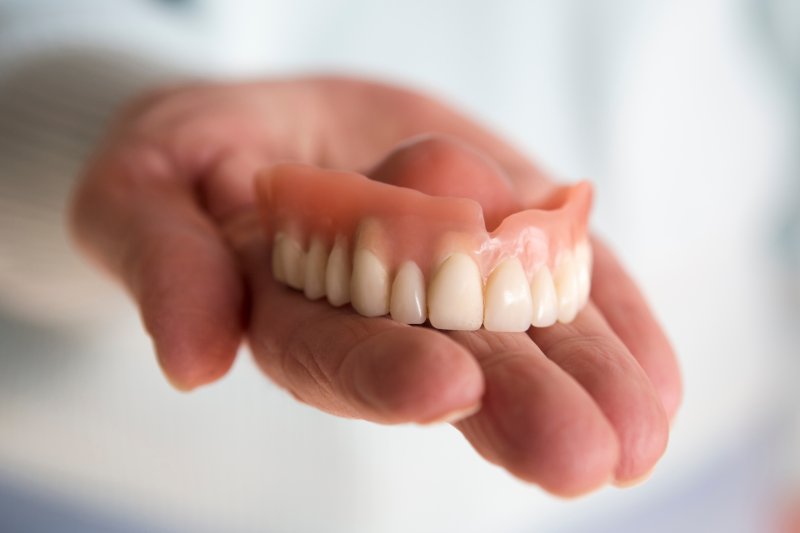 A hand holding an upper denture