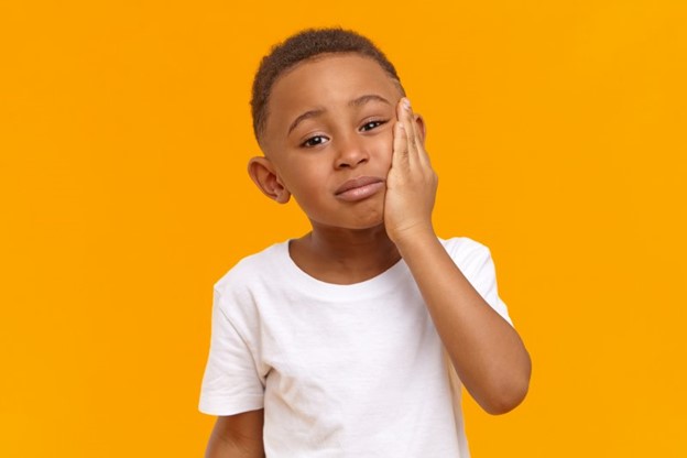 patient suffering from facial pain holding cheek