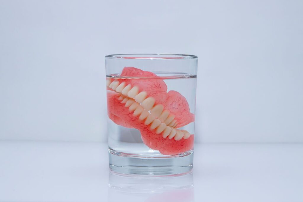 A pair of dentures soaking in a glass of water
