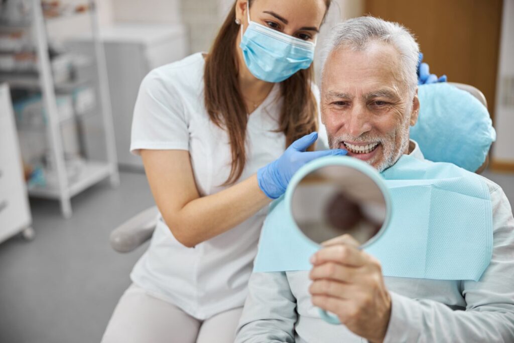A man smiling at his teeth at the dentist’s office
